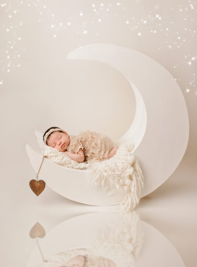 Sleeping newborn baby posed on the moon prop during a professional photoshoot in Preston, Lancashire.