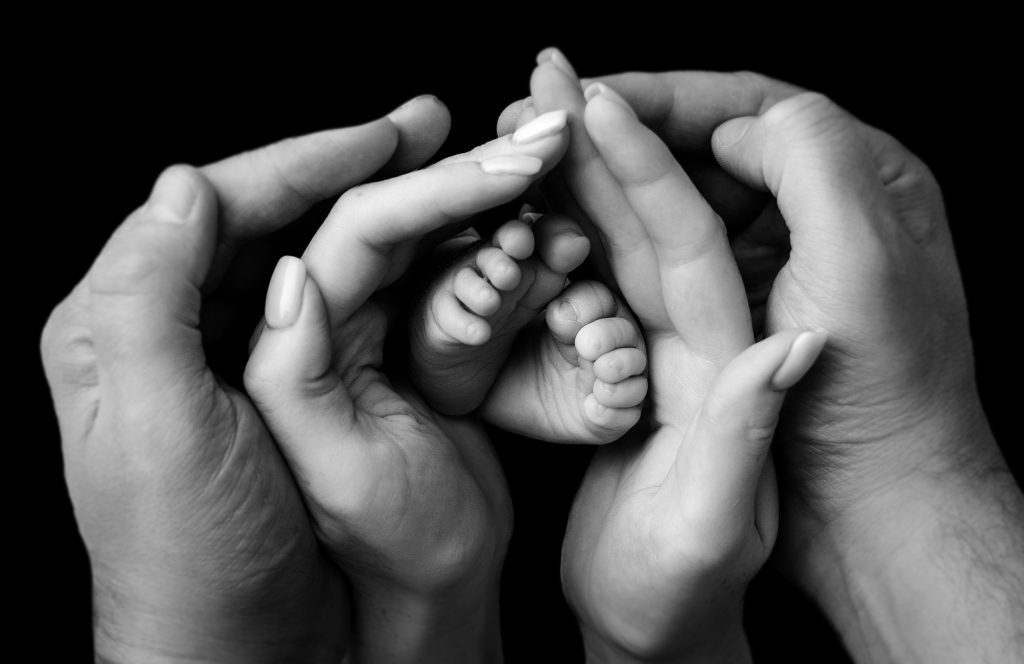 parents holding baby feet on the newborn photoshoot, black and white picture